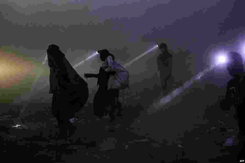 People equipped with searchlights scan for&nbsp;recyclable materials for resale at a landfill in Iraq&#39;s southern city of Basra late at night, June 22, 2023.