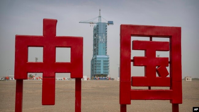 The Shenzhou-16 spacecraft sits atop a Long March rocket covered on a launch pad near characters reading