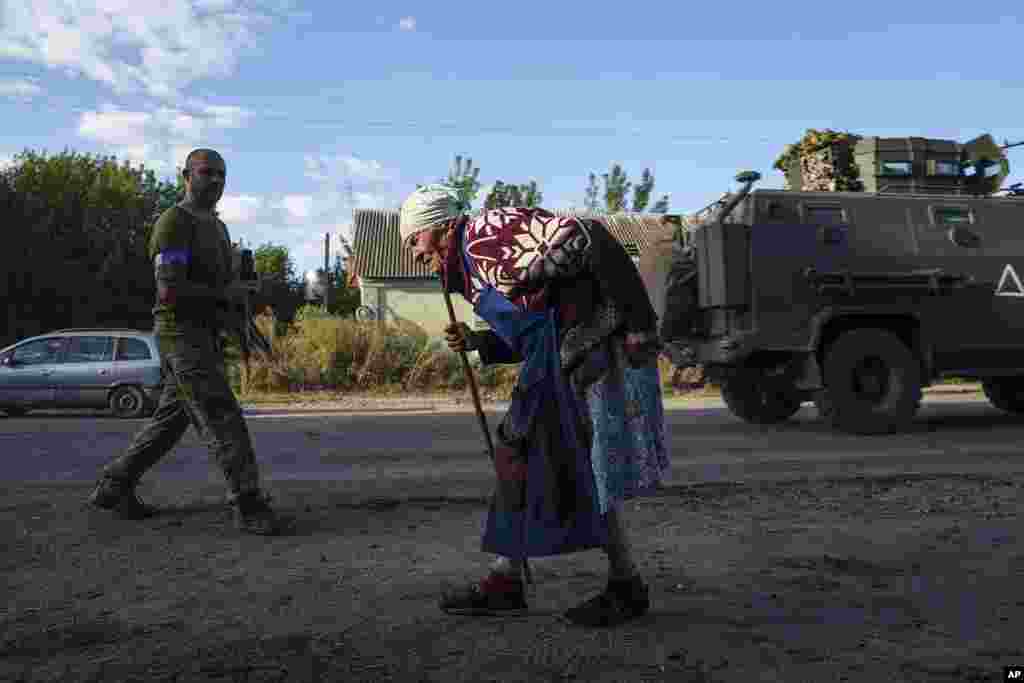 Seorang wanita tua berjalan di sepanjang jalan dekat perbatasan Rusia-Ukraina, wilayah Sumy, Ukraina, 14 Agustus 2024. (AP)