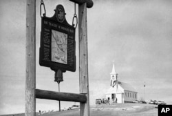 FILE - A historical marker commemorating the Wounded Knee Massacre of Dec. 29, 1890 stands on a road near the Sacred Heart Catholic Church in Wounded Knee, South Dakota, March 8, 1973.