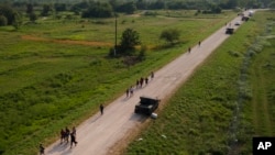 Migrantes caminan por un sendero después de cruzar el Río Grande en la frontera entre Estados Unidos y México, el jueves 11 de mayo de 2023, en Brownsville, Texas.