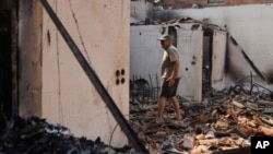 A man surveys a burned house as wildfires blaze near Kirkis, in the northeastern Evros region of Greece, Aug. 23, 2023. Major blazes were also burning in Spain's Tenerife and in northwestern Turkey near the Greek border.