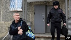 Yevgeny Roizman, mantan walikota dan kritikus Kremlin, berjalan dengan pengawalan petugas polisi di Yekaterinburg, Rusia, Kamis, 16 Maret 2023. (AP Photo/Vladimir Podoksyonov)