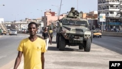 People walk past members of the Senegalese armed forces patrolling the streets in Dakar, on June 2, 2023, following violent protests.