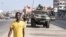 People walk past members of the Senegalese armed forces patrolling the streets in Dakar, on June 2, 2023, following violent protests.