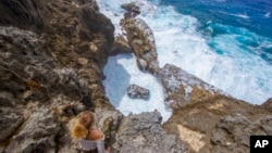 A person sits on a rock face overlooking the ocean in Niue in this 2018 photo. Prime Minister Dalton Tagelagi on Sept. 19, 2023, announced a plan in which individuals or companies can pay $148 to protect 1 square kilometer of ocean.