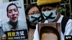 FILE - A pro-democracy activist, left, holds a placard of Chinese citizen journalist Fang Bin, imprisoned for reporting on China's first COVID cases, during a protest outside the Chinese liaison office in Hong Kong, Feb. 19, 2020.