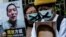 FILE - A pro-democracy activist, left, holds a placard of Chinese citizen journalist Fang Bin, imprisoned for reporting on China's first COVID cases, during a protest outside the Chinese liaison office in Hong Kong, Feb. 19, 2020.