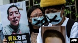 یک فعال دموکراسی‌خواه در هنگ‌کنگ پلاکاردی با تصویر فنگ بین، شهروندخبرنگار چینی، در دست دارد (آرشیو)