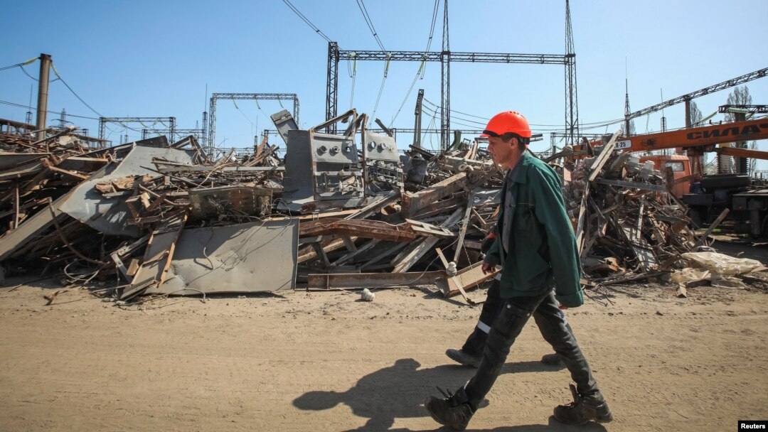 FILE - Employees of a critical power infrastructure installation, hit by a Russian missile strike, walk by its destroyed part, amid Russia's attacks on Ukraine, in Kharkiv, northeastern Ukraine, April 10, 2024.