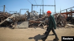 FILE - Employees of a critical power infrastructure installation, hit by a Russian missile strike, walk by its destroyed part, amid Russia's attacks on Ukraine, in Kharkiv, northeastern Ukraine, April 10, 2024.