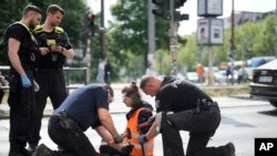 Police officers use hammers and chisels to remove a climate activist who has glued himself to a road during a climate protest in Berlin, Germany, May 22, 2023. 