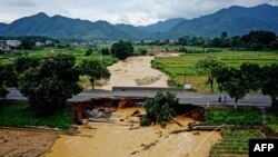 Warga berjalan di jembatan yang rusak setelah badai di Longyan, di Provinsi Fujian, China timur pada 17 Juni 2024. (Foto: CNS/AFP)