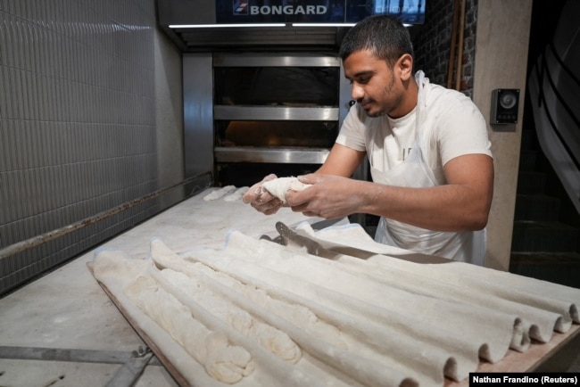 Yasin Robin, a sous-chef baker at Leonie Bakery, prepares baguettes in the kitchen in Paris, France July 22, 2024. (REUTERS/Nathan Frandino)