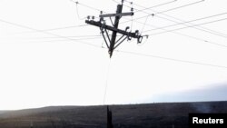 A power pole that was burned by the Smokehouse Creek wildfire hangs from the power lines in Canadian, Texas.