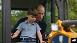 Britain's Prince William is helped by Prince Louis as he uses an excavator while taking part in the Big Help Out, during a visit to the 3rd Upton Scouts Hut in Slough, England, May 8, 2023.