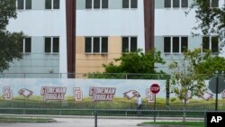 FILE - A security agent walks alongside a barrier surrounding Marjory Stoneman Douglas High School in Parkland, Florida, July 5, 2023. 