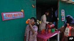 File - Seorang sukarelawan membagikan air minum di samping halte bus pada siang hari di musim panas yang terik di Hyderabad, India, 21 Maret 2024. (AP/Mahesh Kumar A., File)