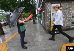 A South Korean government official, left, guides citizens into underground facilities after an air raid siren sounded during a civil defense drill against possible artillery attacks by North Korea in Seoul, Aug. 23, 2023.