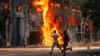 Men run past a shopping center which was set on fire by protesters during a rally against Prime Minister Sheikh Hasina and her government, in Dhaka, Bangladesh, Aug. 4, 2024. 