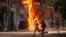 Men run past a shopping center which was set on fire by protesters during a rally against Prime Minister Sheikh Hasina and her government, in Dhaka, Bangladesh, Aug. 4, 2024. 