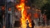 FILE - Men run past a shopping center which was set on fire by protesters during a rally against Prime Minister Sheikh Hasina and her government, in Dhaka, Aug. 4, 2024. 