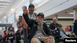 World War II Veteran Cletis Bailey waves as onlookers cheer and offer gratitude for him and a group of World War II Veterans traveling to Normandy, France to commemorate D-Day, in Atlanta, Georgia, June 2, 2024. 