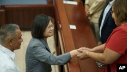 Taiwan's President Tsai Ing-wen, center, shakes hands with a senator at the end of her visit to the National Assembly in Belmopan, Belize, April 3, 2023. Tsai is in Belize for an official three-day visit.