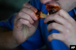 A man eats a chicken wing at a barbecue restaurant in Cincinnati, Ohio, June 12, 2024. A recent study involved questioning over 28,000 people on four continents about what they ate.