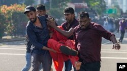 Anggota dari partai oposisi Sri Lanka Partai Kekuatan Rakyat Nasional tampak membawa biksu yang terluka dalam bentrokan dengan polisi di Kolombo, Sri Lanka, pada 26 Februari 2023. (Foto: AP/Eranga Jayawardena)