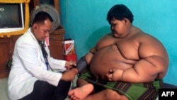 Seorang dokter memeriksa kondisi Arya, anak berusia 10 tahun yang mengalami obesitas, di rumahnya di Karawang, pada 1 Juli 2016. (Foto: AFP/Mahendra)