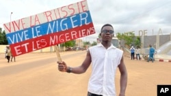 A supporter of Niger's ruling junta holds a placard in the colors of the Russian flag reading 'Long Live Russia, Long Live Niger and Nigeriens' at a protest called to push back against foreign interference in Niamey, Niger, Aug. 3, 2023.