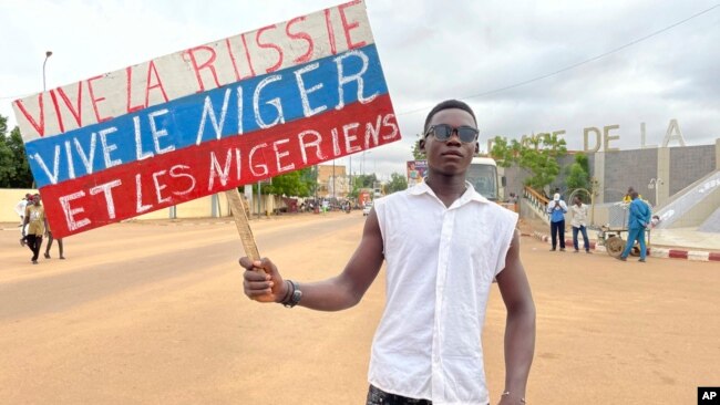 A supporter of Niger's ruling junta holds a placard in the colors of the Russian flag reading 'Long Live Russia, Long Live Niger and Nigeriens' at a protest called to push back against foreign interference in Niamey, Niger, Aug. 3, 2023.