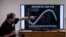 FILE - A professor of the British Antarctic Survey explains a graph on the state of Antarctic sea ice at different years, at the British Antarctic Survey's headquarters in Cambridge, June 19, 2023.