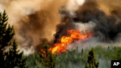 FILE - Flames from a wildfire burn along a ridge top north of Fort St. John, British Columbia, Canada, on July 2, 2023. Canada has seen a record number of wildfires this year. On Aug. 17, 2023, air evacuations were to begin in the capital of the Northwest Territories.