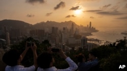 Visitors look at sunset from a hill in Hong Kong, March 22, 2024. 