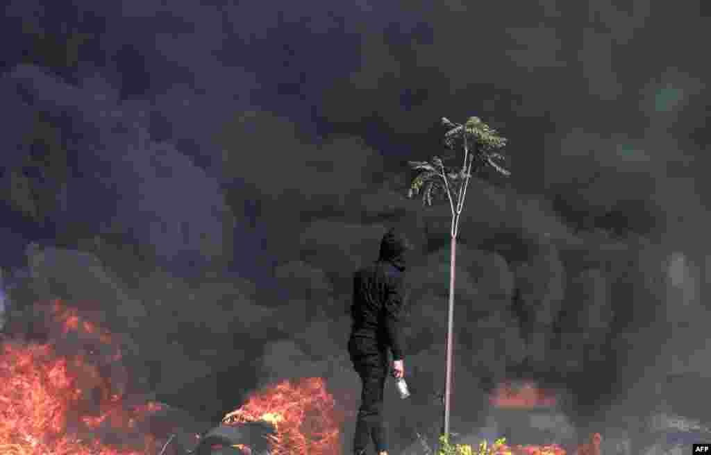 A Palestinian looks at dense black smoke during clashes with Israeli soldiers at the north entrance of the Palestinian city of Ramallah, near Beit El Jewish settlement, in the occupied West Bank.