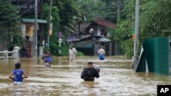 People wade through flood waters in Kelaniya, a suburb of Colombo, Sri Lanka, June 3, 2024.