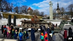 People look at a destroyed Russian T-72B3 tank installed as a symbol to mark the first anniversary of Russia's full-scale invasion of Ukraine, in Freedom Square in Tallinn, Estonia, March 1, 2023.