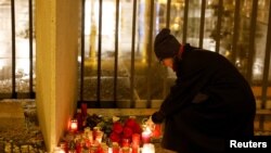 A woman lights a candle in front of the Charles University main building following a mass shooting at one of the university's buildings in Prague, Czech Republic, Dec. 21, 2023.