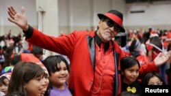 Richard Reyes, berpenampilan Pancho Claus, berpose bersama anak-anak di acara Navidad en el Barrio di Houston, Texas, AS, 16 Desember 2023. (REUTERS/Evan Garcia)