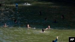 People swim in the Seine river after Paris Mayor Anne Hidalgo swam in the river, July 17, 2024, in Paris.