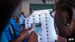 Afisa wa Tume huru ya Taifa ya Uchaguzi (CENI) akiangalia vitambulisho vya wapiga kura huko Kinshasa, on December 20, 2023.