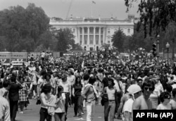 FILE - Anti-war demonstrators raise their hands toward the White House as they protest the shootings at Kent State University and the U.S. incursion into Cambodia, on the Ellipse in Washington D.C., on May 9, 1970. (AP File Photo)