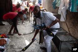 FILE - Community members strike machetes against the ground as they support the "Bwa Kale" movement to fight gangs seeking to take control of their neighborhood in the Delmas district of Port-au-Prince, Haiti, May 28, 2023. (AP Photo/Odelyn Joseph, File)