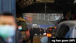 Sejumlah kendaraan yang membawa personel WHO memasuki area pasar hidangan laut Huanan di Wuhan, China, pada 31 Januari 2021. (Foto: AP/Ng Han Guan)