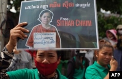 A supporter of Cambodia union leader Chhim Sithar holds up a placard outside Phnom Penh Municipal Court in Phnom Penh on May 25, 2023.