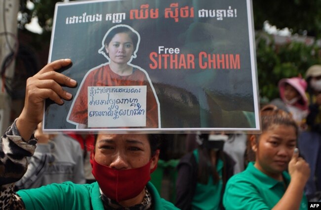 A supporter of Cambodia union leader Chhim Sithar holds up a placard outside Phnom Penh Municipal Court in Phnom Penh on May 25, 2023.