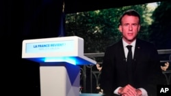 French President Emmanuel Macron appears on television screen at the French far-right National Rally party election night headquarters, in Paris, June 9, 2024. Macron dissolved the National Assembly and called for a new legislative election.