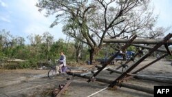 Un residente conduce su motocicleta frente a postes de electricidad caídos en Kyauktaw, en el estado de Rakhine, en Myanmar, el 15 de mayo de 2023, después de que el ciclón Mocha se estrellara contra la costa.